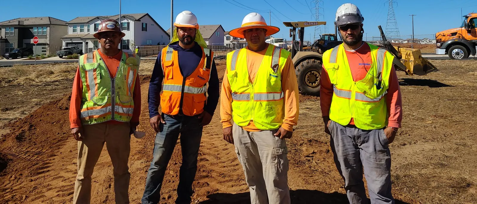 Marina crew in hard hats and high-visibility vests at a grading site